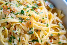 a bowl filled with pasta covered in parmesan cheese and garnished with herbs