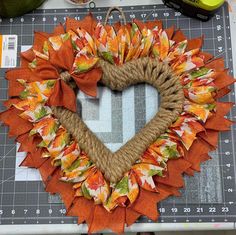 a heart shaped wreath made out of burlock and twine on top of a cutting board