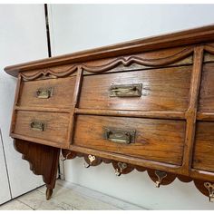 an old wooden dresser with brass handles and knobs on the bottom drawer, next to a white wall