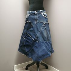 "Upcycled denim patchwork skirt with frayed seams for a distressed look. Decorative metal studs on pockets. Waist measures 32\" and length is approximately 29\"." Recycled Denim Patchwork Denim Skirt, Recycled Denim Patchwork Skirt, Denim Blue Patchwork Skirt From Recycled Denim, Patchwork Denim Skirt In Recycled Denim Blue, Recycled Denim Blue Skirt With Patchwork, Dark Wash Denim Skirt With Patchwork, Upcycle Jeans Skirt, Upcycled Denim Skirt, Patchwork Denim Skirt