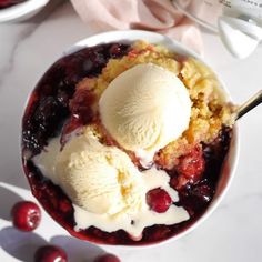 two scoops of ice cream sit in a bowl with cherries on the side