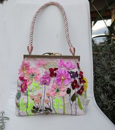 a handbag with flowers on it sitting on a white chair next to some plants