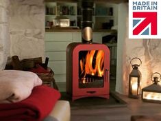 a red stove sitting in the middle of a living room next to a fire place