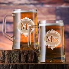 two beer mugs sitting next to each other on top of a tree stump in front of a wooden background