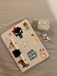 an open notebook with stickers on it next to earbuds