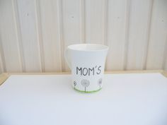 a cup with the word mom's written on it sitting on top of a table