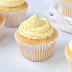 several cupcakes with white frosting sitting on a table next to each other