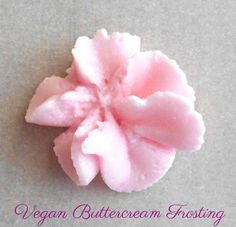 a pink flower that is on top of a gray surface with the words vegan buttercream frosting