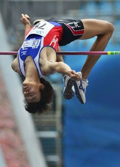 a man is high in the air while holding onto a pole with his hands and feet