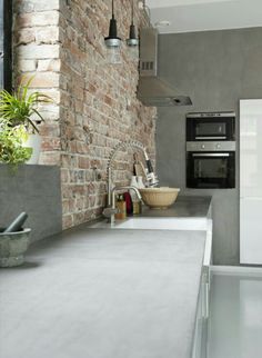 a kitchen with a brick wall and white counter tops