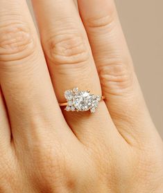 a woman's hand with a three stone ring on her left and an engagement ring on the right