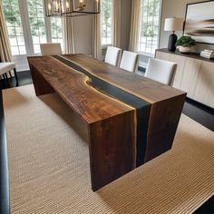 a large wooden table sitting in the middle of a living room next to a window