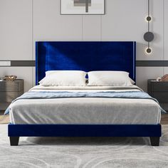 a bed with blue velvet headboard and foot board in a white room, surrounded by grey rugs