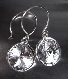 Captivating earrings with brilliant Swarovski crystals in pure crystal-white, sparkling rays of light. These crystals are nestled into bright silver settings and un-fussily suspended from modern, rounded sterling silver earring wires, handmade by me. Traditional French earring hooks also available (not shown). Round rivoli Swarovski crystals: 12mm (1/2" dia) Bezel settings: 14mm (over over 1/2" dia) Total length: just over 1-1/4" (32mm) including large round earring hooks Clear Crystal Earrings, Round Earring, Rays Of Light, Earring Wires, Crystal White, Swarovski Crystal Earrings, Earring Hooks, Large Earrings, Silver Earring