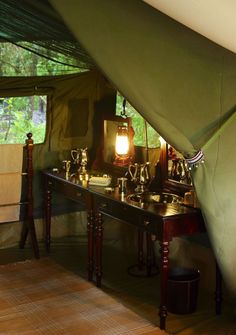 the inside of a tent with two tables and lamps on top of it, in front of a window