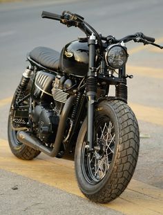 a black motorcycle parked on the street next to a curb with no one around it