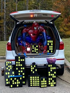 a spiderman is sitting in the back of a car with its trunk open and it's lights turned on