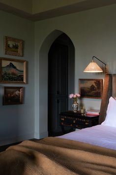 a bed sitting in a bedroom next to a wall with pictures hanging on the walls