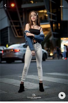 a beautiful young woman standing in the middle of a street