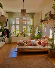 a bed sitting in a bedroom next to a window filled with potted plants and greenery