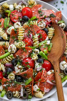 a bowl filled with pasta salad and a wooden spoon