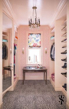 the closet is decorated in pink and black with a chandelier hanging from the ceiling