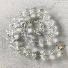 We love the look of this vintage clear lucite (acrylic) round beads statement necklace! Each bead is 5/8" or 16mm in diameter. The necklace can be worn from 17" to 20" long, depending on where the hook is clasped along the wired wrap bead chain. The clasp is gold plated, and the necklace is unsigned. It is in excellent condition, a really fun statement necklace. Clear Glass Round Bead Necklaces, Clear Glass Round Beads Necklaces, Clear Glass Beaded Necklaces, Clear Glass Necklaces With Round Beads, Clear Single Strand Crystal Necklace With Round Beads, Clear Crystal Single Strand Necklace With Round Beads, Clear Crystal Necklace With Single Strand Of Round Beads, Vintage Clear Round Necklace, Adjustable Clear Necklace