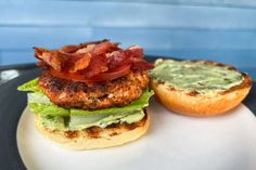 a bacon and lettuce sandwich on a plate next to an open bagel