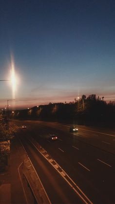 the sun is shining brightly in the sky over an empty highway at night with cars driving on it