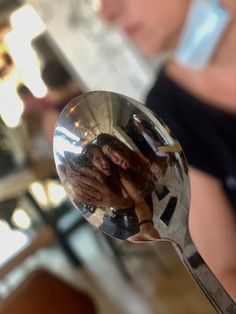 a spoon with some food on it in front of a woman's face and her reflection