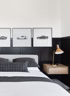 a bed with three framed cars on the headboard and two nightstands next to it