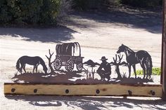 a metal horse and buggy with people in the background on a dirt road next to trees