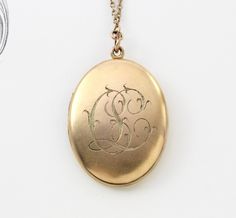 "A fantastic large-sized antique yellow gold-filled locket with a bloomed finish and applied Etruscan style wire-work filigree decoration. The filigree pattern is reminiscent of a William Morris print with its gracefully exuberant arrangement of scrolls framing the stone. The back has been engraved with the initials \"C.L.\" in rich foliate ribbon script. Measuring approximately locket 1 5/8\" inches north to south and 1 1/4\" east to west; the locket opens to reveal a gilded interior with space Ceremonial Yellow Gold Jewelry With Antique Finish, Victorian Oval Filigree Jewelry, Victorian Yellow Gold Locket Necklace For Formal Occasions, Ornate Oval Jewelry With Antique Finish, Elegant Hallmarked Locket Necklace For Wedding, Elegant 14k Gold Locket Necklace With Vintage Charm, Anniversary Filigree Yellow Gold Locket Necklace, Elegant Oval Link Locket Necklace For Wedding, Elegant Oval Pendant Jewelry With Antique Finish