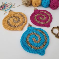 three crocheted purses sitting on top of a table next to balls of yarn