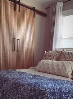 a bed sitting next to a wooden closet in a bedroom