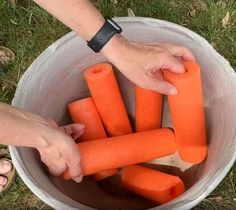 a person holding carrots in a bucket on the ground with their hands over them