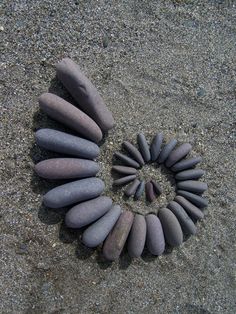 several rocks arranged in the shape of a spiral on a sandy beach with sand and gravel