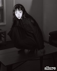 black and white photograph of a woman kneeling on a table