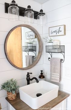 a bathroom sink under a round mirror next to a wooden counter top with soap dispensers on it