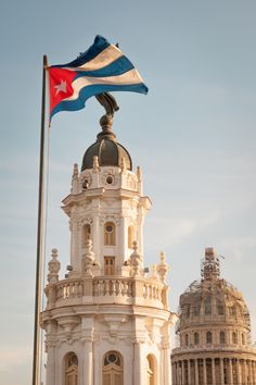 a flag flying on top of a building next to a large dome with a clock