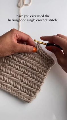 two hands crocheting the ends of a knitted bag with scissors and yarn