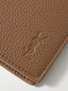 SAINT LAURENT's 'Cassandre' logo was introduced in 1961 and has been a marker of quality ever since. Debossed with the motif at the front, this bifold wallet is all you need on the go, it's made from full-grain leather and opens to a sizeable bill sleeve and plenty of card slots. Classic Business Wallet With Engraved Logo, Classic Business Wallets With Engraved Logo, Designer Leather Wallet With Smooth Grain, Classic Leather Wallet With Logo Plaque, Classic Leather Wallets With Logo Plaque, Designer Leather Wallet With Embossed Logo, Textured Leather Bifold Wallet For Business, Classic Leather Wallets With Engraved Logo, Classic Bifold Wallet With Engraved Logo