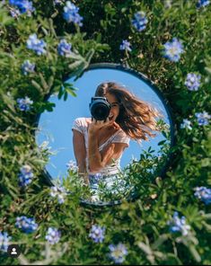 a woman taking a selfie in front of a mirror with blue flowers around her