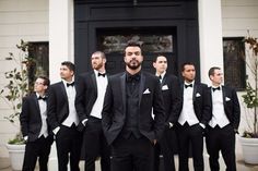 a group of men wearing tuxedos standing in front of a door