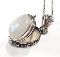 a large white stone in a silver box on a chain