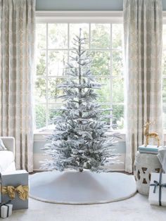 a white christmas tree sitting in front of a window