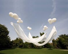 white balloons are floating in the air over a field