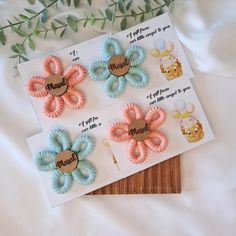 three different colored hair ties on top of a white sheet next to some green leaves