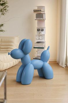 a blue balloon dog sitting on top of a hard wood floor next to a white couch