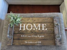 a wooden sign with the words home and a potted plant on it's side